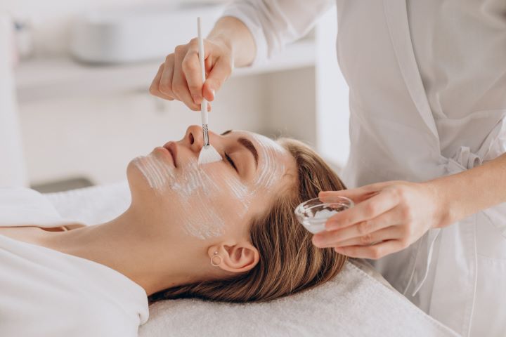 cosmetologist doing face treatment applying face mask