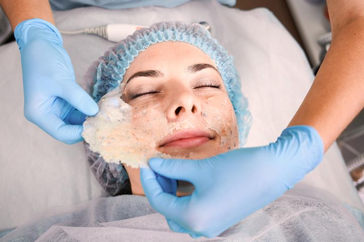 cosmetologist removing cosmetic mask from woman face