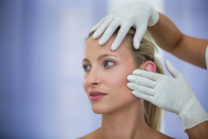 doctor examining female patients face from cosmetic treatment